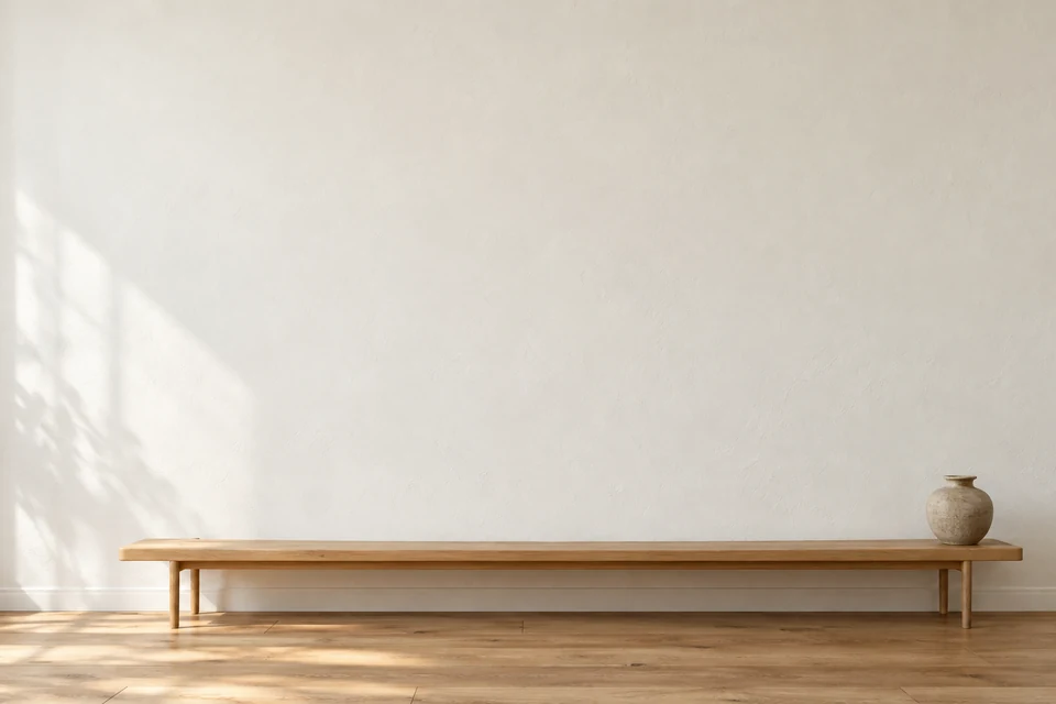 An illustrative room with a blank plaster wall and an oak bench.